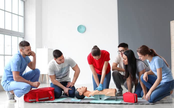 Instructor demonstrating CPR on mannequin at first aid training