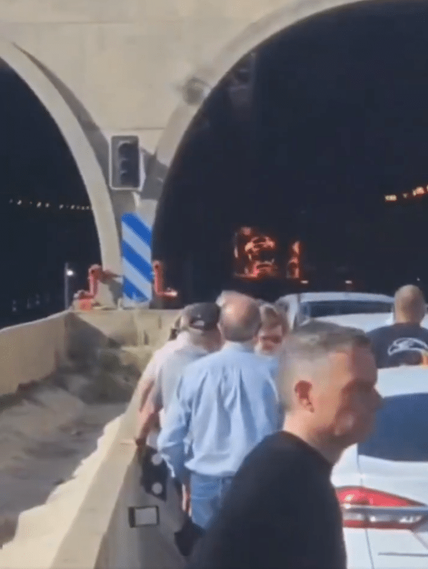 Los conductores atrapados en la desembocadura del túnel con el camión volcado en llamas en la distancia